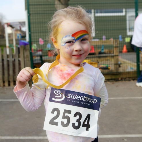 A girl shows her Rainbow Mile medal