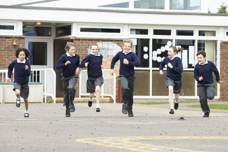 children in school uniform running in a playground