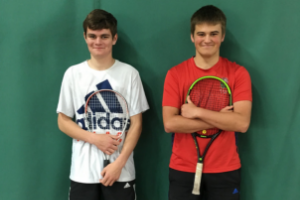 2 young tennis coaches holding tennis rackets