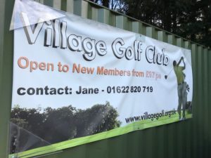 Banner promoting Village Golf Club displayed on a gate outside the club.