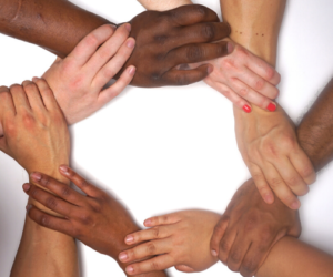 Hands of eight people from different ethnic backgrounds forming a connected circle.